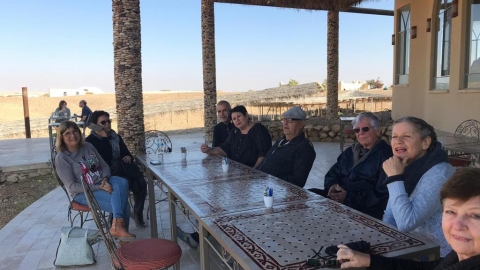 קבוצת מבוגרים יושבים סביב שולחן ומחייכים